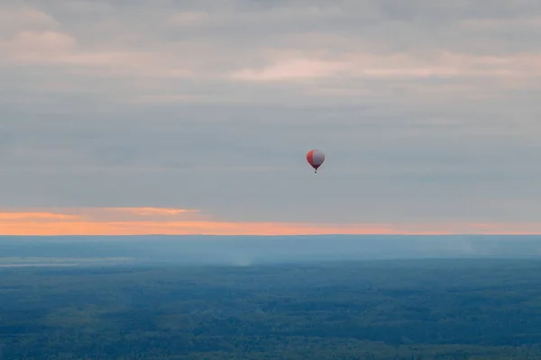 Kolorowy balon wysoko nad ziemią na niebie o zachodzie słońca w f — Zdjęcie stockowe