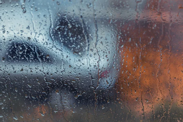 Regentropfen am Fenster. Außerhalb des Fensters verschwommen Auto und Herbst l — Stockfoto