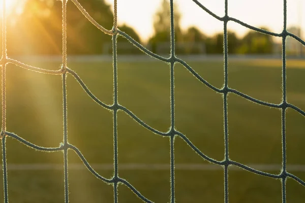 Netting on a football goal in the sunset light on an empty field. Close up.