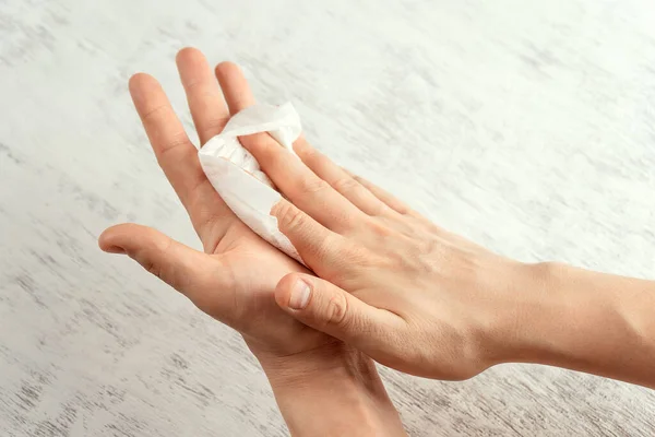 Bir adam ellerini antibakteriyel ıslak bezle siliyor..