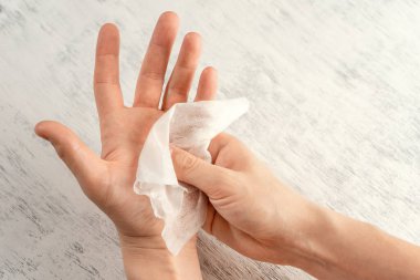 Bir adam ellerini antibakteriyel ıslak bezle siliyor..