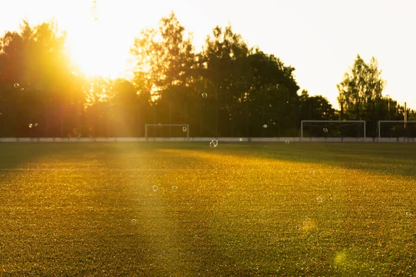 An empty soccer field in the sun. An empty Playground at sunset.