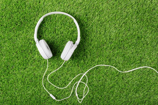White headphones on a green grass. Top of view