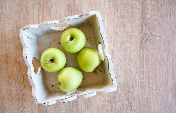 Green apples in white wooden tray on the table