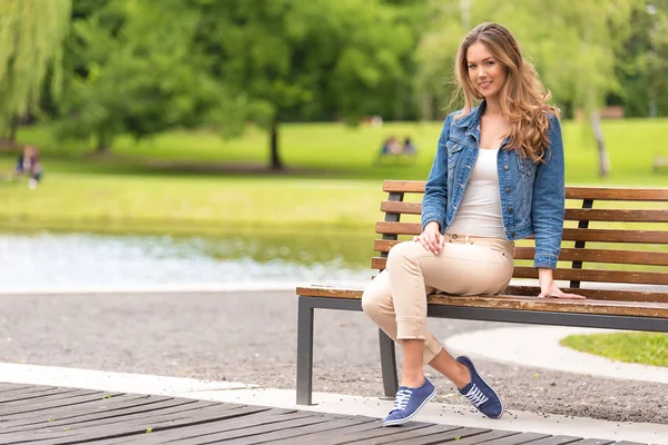 公園のベンチに座っている若い女性は — ストック写真
