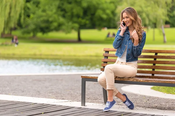 公園のベンチに座っている若い女性は — ストック写真