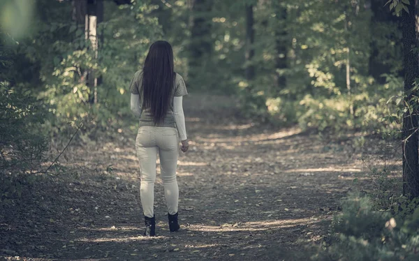 暗い森の中を歩くきれいな女性 背面図 — ストック写真