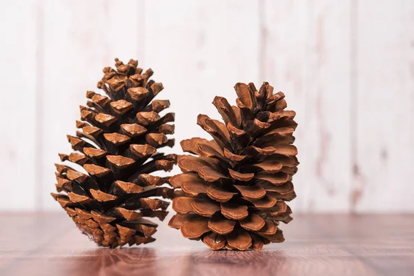 Ahşap dokulu bir arka plan üzerinde iki büyük çam kozalakları