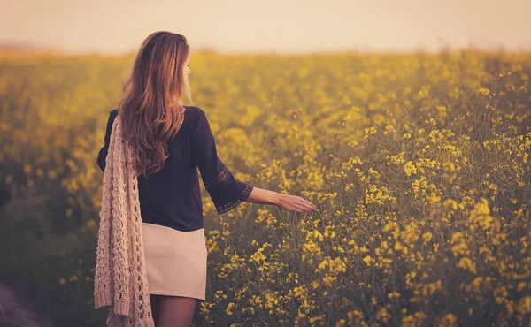 Hermosa mujer caminando en campo de colza . — Foto de Stock