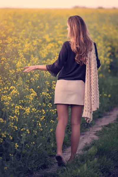 菜種畑を歩く美しい女性. — ストック写真