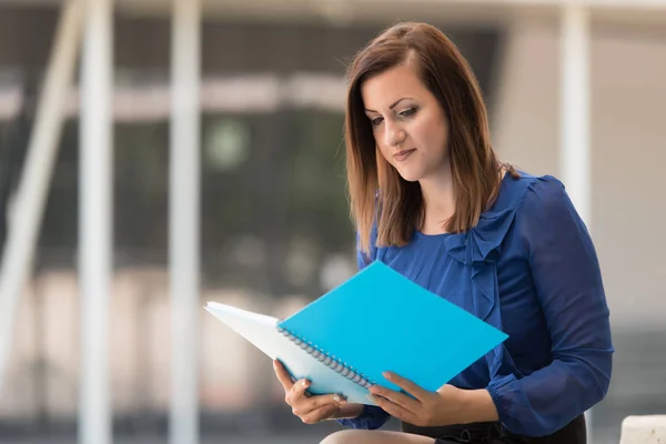 Junge Studentin liest ein blaues Buch — Stockfoto