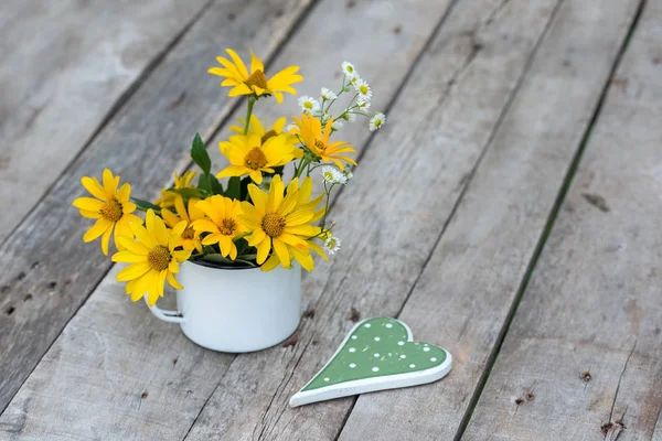 Gele bloem in de beker op de houten tafel — Stockfoto