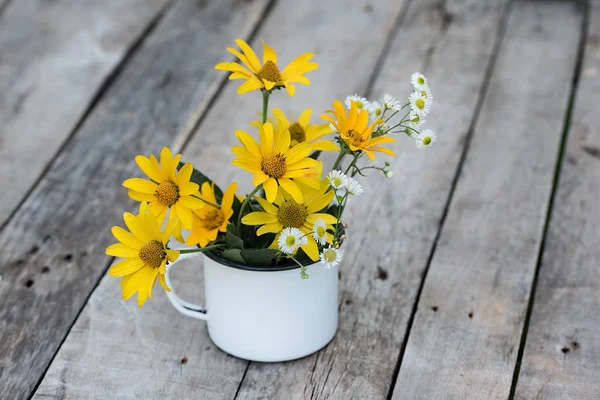 Gele bloem in de beker op de houten tafel — Stockfoto
