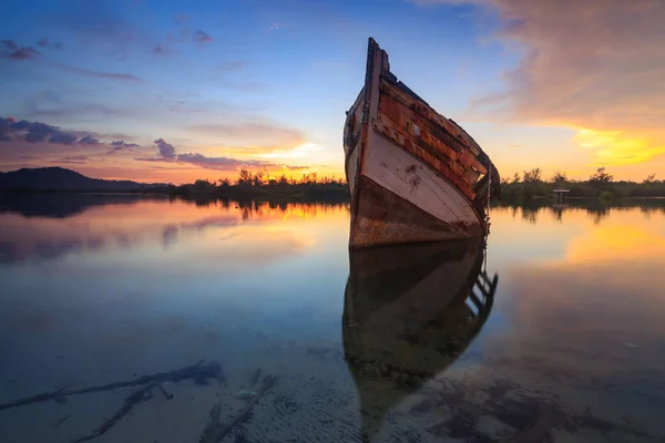 日没の瞬間に反射と岸 ボルネオ 古い漁船で古い大破を放棄します — ストック写真