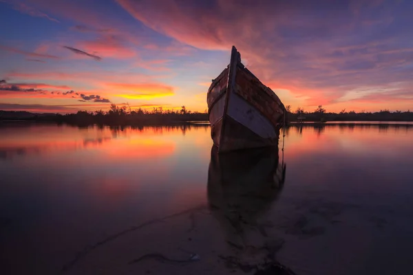 日没の瞬間に反射と岸 ボルネオ 古い漁船で古い大破を放棄します — ストック写真