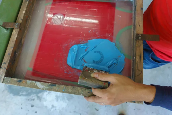 screen printing shirt, blue color is printing on t-shirt with hands pressure