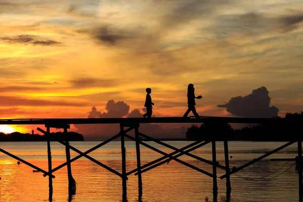 マレーシア サバ州コタキナバル Belud Mantanani 島で日没時に木製の桟橋上シルエット子供を歩く — ストック写真