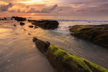 Deniz dalgası ile şaşırtıcı alacakaranlık deniz manzarası Kuala Penyu, Sabah, Borneo 'da yeşil yosunlara çarpıyor. Resim uzun pozlama nedeniyle yumuşak odak ve bulanıklık içerebilir.