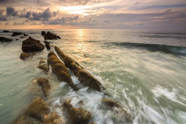 Deniz dalgası ile şaşırtıcı alacakaranlık deniz manzarası Kuala Penyu, Sabah, Borneo 'da yeşil yosunlara çarpıyor. Resim uzun pozlama nedeniyle yumuşak odak ve bulanıklık içerebilir.