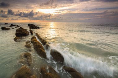 Deniz dalgası ile şaşırtıcı alacakaranlık deniz manzarası Kuala Penyu, Sabah, Borneo 'da yeşil yosunlara çarpıyor. Resim uzun pozlama nedeniyle yumuşak odak ve bulanıklık içerebilir.