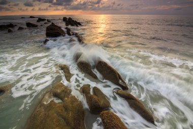 Deniz dalgası ile şaşırtıcı alacakaranlık deniz manzarası Kuala Penyu, Sabah, Borneo 'da yeşil yosunlara çarpıyor. Resim uzun pozlama nedeniyle yumuşak odak ve bulanıklık içerebilir.