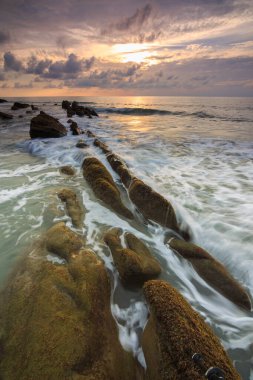 Deniz dalgası ile şaşırtıcı alacakaranlık deniz manzarası Kuala Penyu, Sabah, Borneo 'da yeşil yosunlara çarpıyor. Resim uzun pozlama nedeniyle yumuşak odak ve bulanıklık içerebilir.