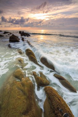 Deniz dalgası ile şaşırtıcı alacakaranlık deniz manzarası Kuala Penyu, Sabah, Borneo 'da yeşil yosunlara çarpıyor. Resim uzun pozlama nedeniyle yumuşak odak ve bulanıklık içerebilir.