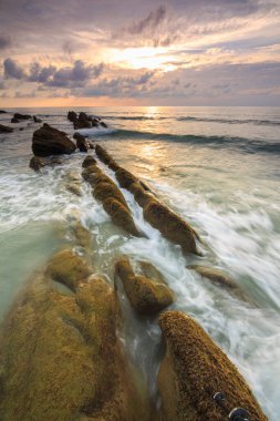 Deniz dalgası ile şaşırtıcı alacakaranlık deniz manzarası Kuala Penyu, Sabah, Borneo 'da yeşil yosunlara çarpıyor. Resim uzun pozlama nedeniyle yumuşak odak ve bulanıklık içerebilir.