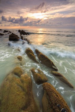 Deniz dalgası ile şaşırtıcı alacakaranlık deniz manzarası Kuala Penyu, Sabah, Borneo 'da yeşil yosunlara çarpıyor. Resim uzun pozlama nedeniyle yumuşak odak ve bulanıklık içerebilir.