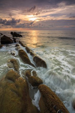 Deniz dalgası ile şaşırtıcı alacakaranlık deniz manzarası Kuala Penyu, Sabah, Borneo 'da yeşil yosunlara çarpıyor. Resim uzun pozlama nedeniyle yumuşak odak ve bulanıklık içerebilir.