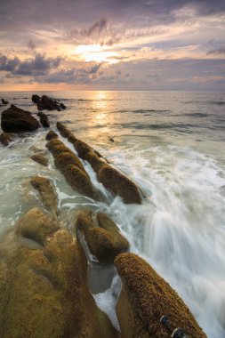 Deniz dalgası ile şaşırtıcı alacakaranlık deniz manzarası Kuala Penyu, Sabah, Borneo 'da yeşil yosunlara çarpıyor. Resim uzun pozlama nedeniyle yumuşak odak ve bulanıklık içerebilir.