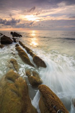 Deniz dalgası ile şaşırtıcı alacakaranlık deniz manzarası Kuala Penyu, Sabah, Borneo 'da yeşil yosunlara çarpıyor. Resim uzun pozlama nedeniyle yumuşak odak ve bulanıklık içerebilir.