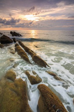 Deniz dalgası ile şaşırtıcı alacakaranlık deniz manzarası Kuala Penyu, Sabah, Borneo 'da yeşil yosunlara çarpıyor. Resim uzun pozlama nedeniyle yumuşak odak ve bulanıklık içerebilir.