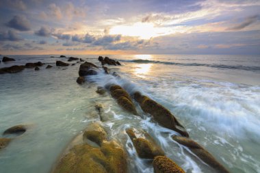 Deniz dalgası ile şaşırtıcı alacakaranlık deniz manzarası Kuala Penyu, Sabah, Borneo 'da yeşil yosunlara çarpıyor. Resim uzun pozlama nedeniyle yumuşak odak ve bulanıklık içerebilir.