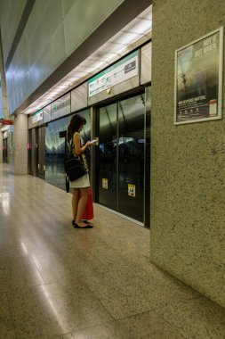 Singapur - Temmuz 07, 2017: Sırt çantalı tanımlanamayan bir adam Singapur 'a MRT treninin gelmesini beklerken akıllı telefon çalıyor.