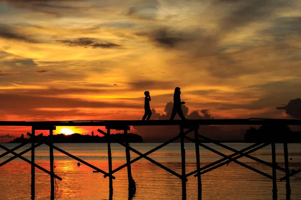 シルエットの子供は マレーシアのサバ州コタベルドのMantanani島で日没の間に木製の桟橋で幸せに走ります — ストック写真