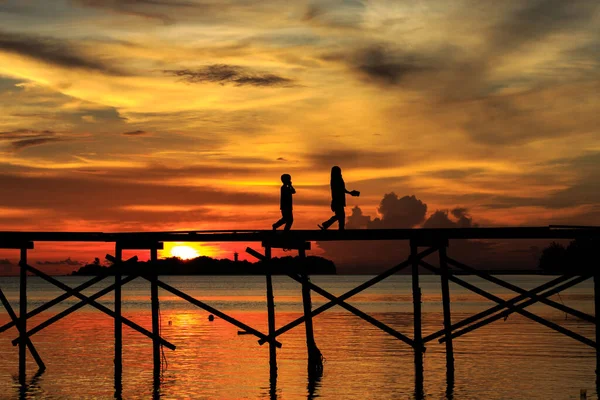 シルエットの子供は マレーシアのサバ州コタベルドのMantanani島で日没の間に木製の桟橋で幸せに走ります — ストック写真