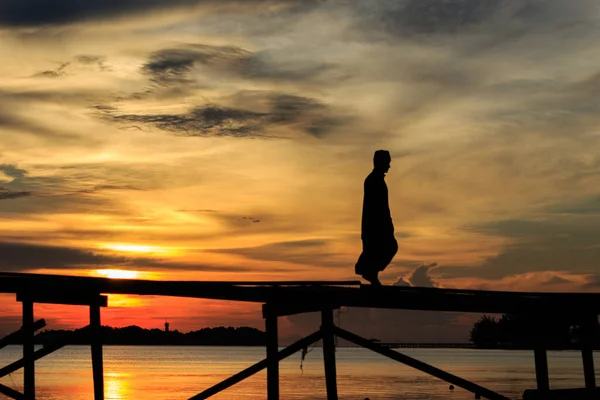 シルエットイスラム教徒の男は マレーシアのサバ州コタベルドのMantanani島で日没の間に木製の桟橋を歩きます — ストック写真
