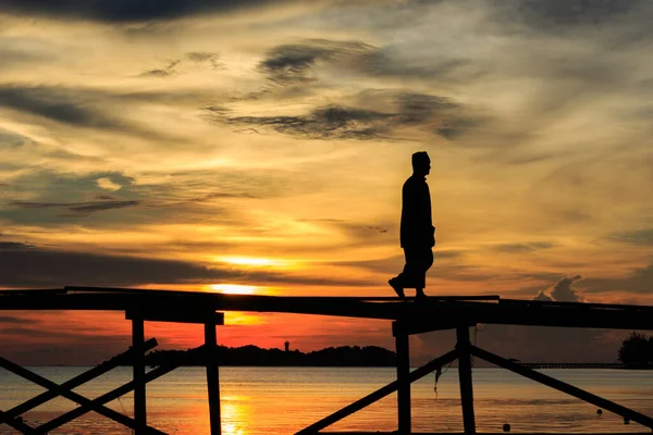 シルエットイスラム教徒の男は マレーシアのサバ州コタベルドのMantanani島で日没の間に木製の桟橋を歩きます — ストック写真