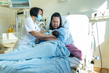 Kota Kinabalu, Sabah, Malezya-30 Mayıs 2020: Ebe, yeni doğan bebek ve anneye Kota Kinabalu, Sabah, Malezya 'daki doğum odası hastanesinde emzirilmesine yardım ediyor