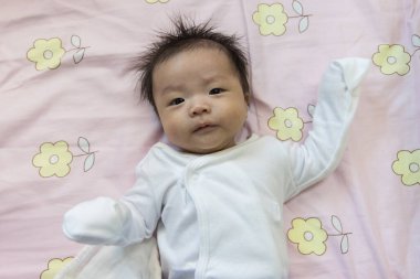Yatakta yatan Asyalı şirin bir bebeğin portresi.