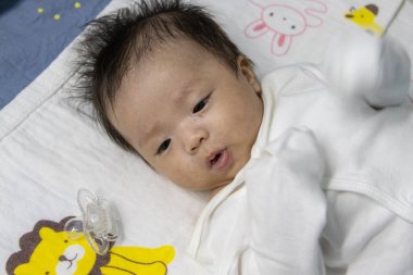 İki aylık Asyalı, tatlı bir bebeğin yatakta yatışı portresi.