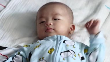 Sevgili Asyalı bebek uyandı ve uyandıktan sonra gülümsedi. Sağlıklı Sevimli Bebek Gülüşü.