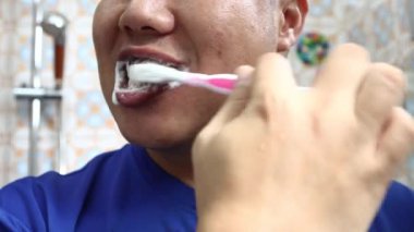 Çinli bir adamın evde dişlerini fırçalaması. Kapatın. Ön görünüm.