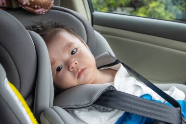 Yerel yaşam tarzı Asyalı Çinli bebek mutlu gülümseyen beyaz çocuk emniyet oto koltuğuna oturur.