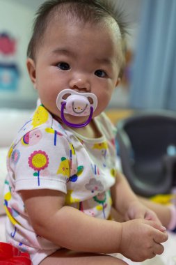 Sevimli bir kızın portresi. Yatakta oturan 6 aylık bebek.