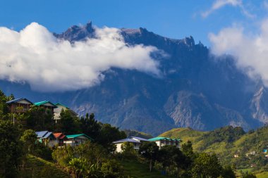 Kinabalu Dağı, güneşli ve açık bir günde mavi gökyüzü olan, yemyeşil Kundasang 'ın görkemli manzarasına hükmediyor.