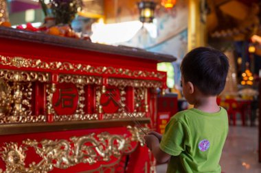 Genç çocuk Çin tapınağında elinde tütsü çubuklarıyla dua ediyor.