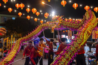 Kota Kinabalu, Sabah, Malezya - 16 Şubat 2024: Çin Yeni Yıl kutlamaları sırasında geleneksel kıyafet giymiş bir grup insan sokakta ejderha dansı yapıyor