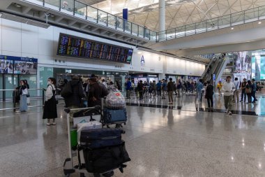 Hong Kong, Çin - 21 Mart 2024: Hong Kong Uluslararası Havaalanı 'ndaki varış salonunda bavullu turist grubu